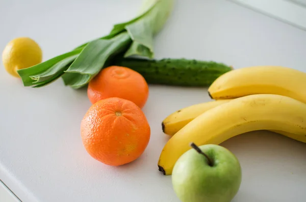 Verstreut verschiedene Früchte Bündel von frischen reifen Bananen, Orangen, Mandarinen auf weißem Tisch in der Küche. Gesundes Essen. Nahaufnahme — Stockfoto