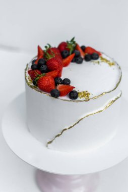 Beyaz arka planda peynir kremalı, kremalı, çikolatalı ve taze meyveli güzel bir pasta. Düğün pastası mı yoksa doğum günü pastası mı?.