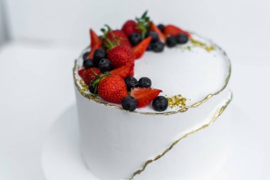 Beyaz arka planda peynir kremalı, kremalı, çikolatalı ve taze meyveli güzel bir pasta. Düğün pastası mı yoksa doğum günü pastası mı?.