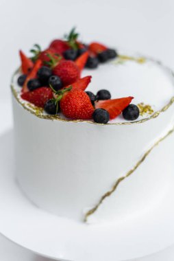 Beyaz arka planda peynir kremalı, kremalı, çikolatalı ve taze meyveli güzel bir pasta. Düğün pastası mı yoksa doğum günü pastası mı?.