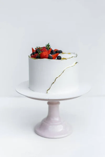Гарний білий торт з сирним кремом, зливається, шоколад і свіжі ягоди на білому тлі. Оригінальна ідея для весільного торта або торта на день народження . Ліцензійні Стокові Зображення
