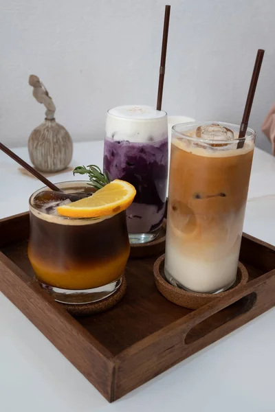 Tutku meyvesi ve portakal suyu ile shot kahve. Mor patates çayı. Buzlu kahve. Bir bardak buzlu soğuk kahve. Camın önü odaklı. Meşe ağacından bir tabakta portakal karışımlı buzlu kahve. Mor patates çayı.