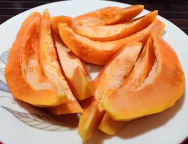 Beyaz tabakta dilimlenmiş olgun papaya.