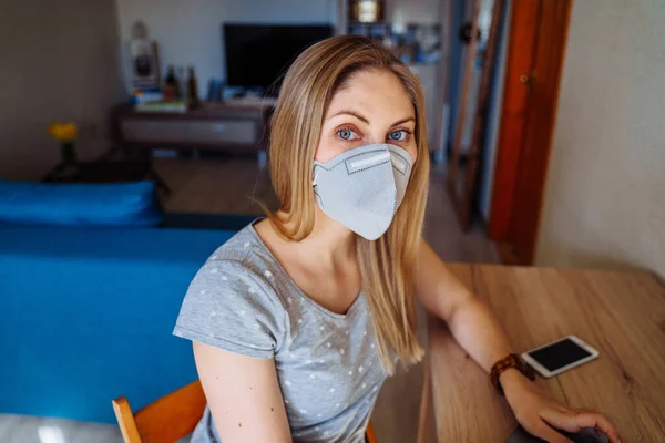 Menina Bonita Sentada Casa Olhando Para Câmera Usando Máscara Protetora — Fotografia de Stock