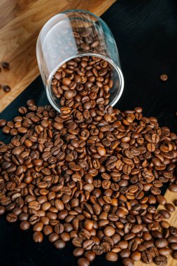 Kahve üzerine dökülen şeffaf bardaklar kavrulmuş fasulyeler kafedeki ahşap kahverengi ve siyah masada..