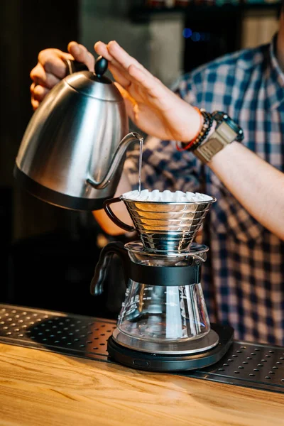 Alternative Coffee Brewing Method. Close-up of barista hand pouring water from the kettle to coffee filter purover in the restaurant.