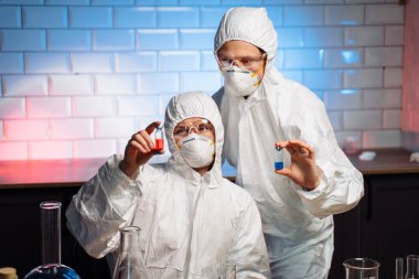 Coronavirus aşısı geliştirme. Koruyucu giysiler, maskeler ve gözlükler içindeki araştırmacılar, mataralar ve test tüpleri kullanarak bileşikleri sentezleme ve pas sıvısı arayışı içinde deneyler yapıyorlar..