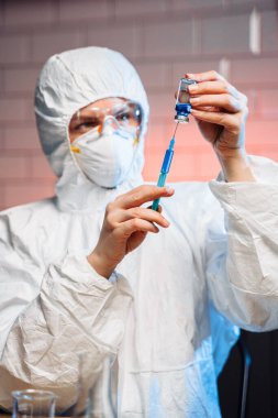 Coronavirus aşısı geliştirme. Biyokimya laboratuarı araştırmaları için bilimsel ve tıbbi laboratuvar enstrümanı. Kimyager laboratuvarda kimyasal sıvı şırıngası ile numune analiz ediyor.