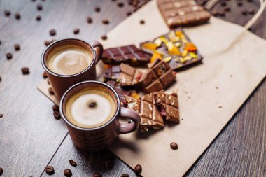 Tahıllı iki fincan espresso kahve, el işi çanta ve siyah arka plandaki ahşap bir masada çikolata. Üst Wiev.