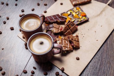 Tahıllı iki fincan espresso kahve, el işi çanta ve siyah arka plandaki ahşap bir masada çikolata. Üst Wiev.