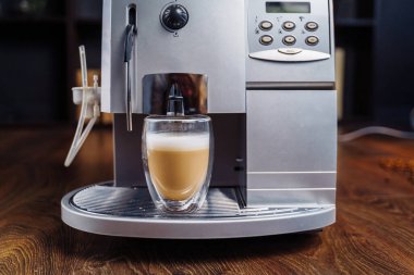 Kahve espresso makinesinden taze kahve yapmak. Cam şeffaf kahve fincanında kapuçino yapmak. Bütçe kahve makinesi.