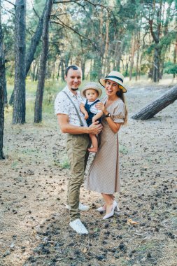 Uzun vadeli plan. Dışarıda mutlu aile yürüyüşleri. Baba çocuğu kucağında tutuyor ve onunla oynuyor. Birlikte mutlular. Arka planda gün batımındaki ağaçlar. Çiçekleri ve yumuşak oyuncak renkli zürafayı tut.