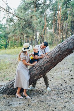 Mutlu genç aile yaz ormanlarında koşuştururken eğleniyor. Babam elinde bir yaşındaki bir çocuk çocuğu tutuyordu. Ebeveynler mutlu mesut zıplıyorlar ve şehir dışında iyi vakit geçiriyorlar.