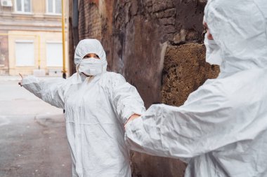 Koruyucu giysili kadın doktor ve sağlık maskesi hayat kurtarmak için doktor çekiyor. Korkuyorlar ama insanlara yardım etmeye hazırlar. Nereye gidileceğini gösteren bir kadın. Coronavirus konsepti. Covid 19