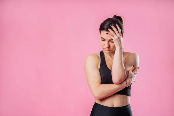 Portrait of unhappy upset woman frowns her face, about to cry, being unhappy as she cannot achieve goals, isolated on pink studio background. Upset worried girl having headache touching face and head