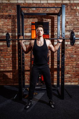 Sporcu spor salonunda bir antrenörün gözetiminde çapraz uyum sağlıyor. Spor salonunda bir adam çıtayı yükseltiyor. Ağırlık kaldırma. Duygusal, güçlü, kaslı sporcu. Egzersiz yapıyor.