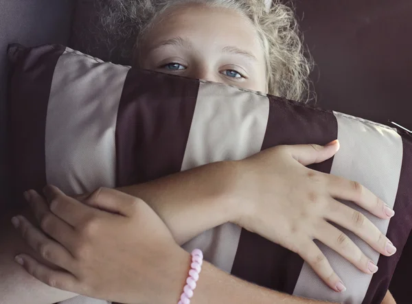 Chica está escondiendo su cara por la almohada rayada — Foto de Stock