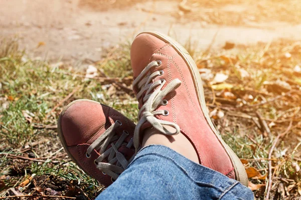 Feet in red sneakers and jeans outdoors. — Stock Photo, Image