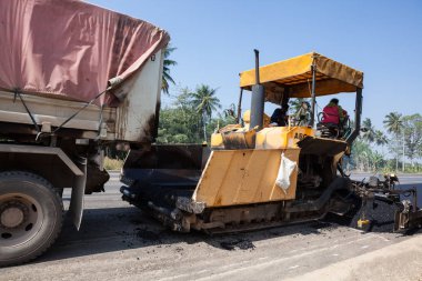 Bir asfalt makinesi ve bir kamyon römork ile