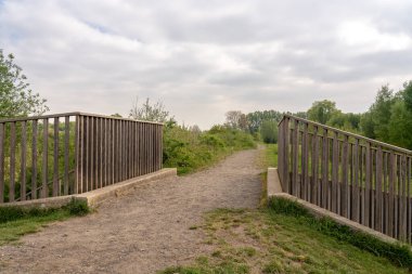 Bulutlu bir günde, bu yürüyüş yolu doğanın ortasında tahta bir köprüden geçer.