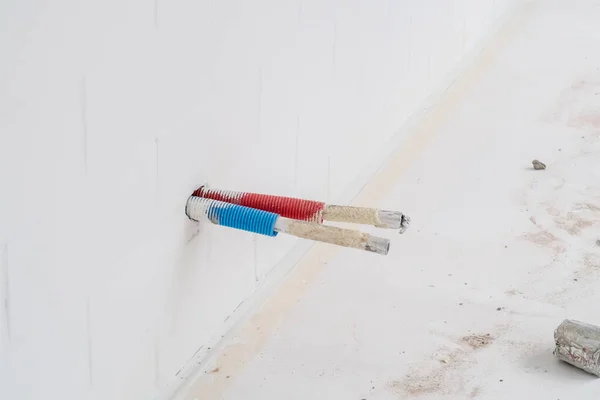 new plastic pipes for hot and cold water are coming out of the wall