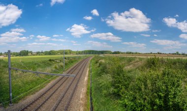 Tren rayları bulutlu gökyüzüyle ufukta kayboluyor.