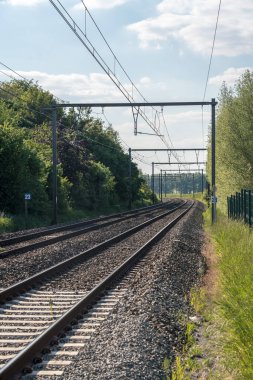Tren rayları bulutlu gökyüzüyle ufukta kayboluyor.