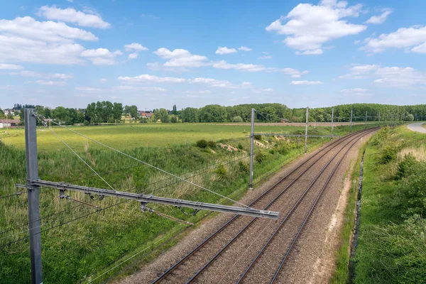 Tren rayları bulutlu gökyüzüyle ufukta kayboluyor.