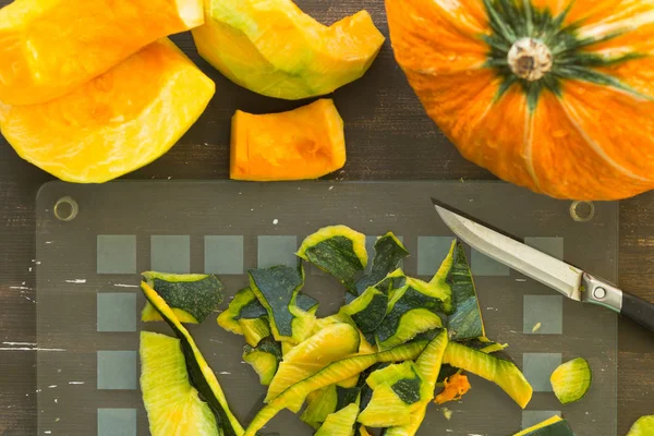 Stripes on glass cutting board after peeling pumpkin on wooden background