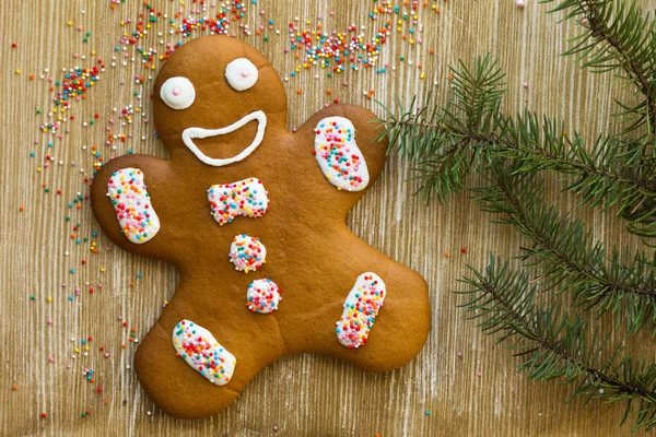 Baked decorated gingerbread cookie man on wooden background