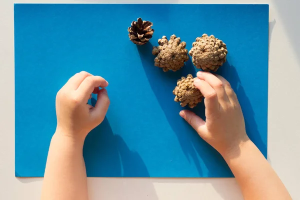 Vista superior de manos infantiles jugando con conos sobre el fondo azul —  Fotos de Stock