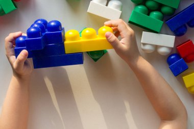 Çocuk eli çok renkli bloklarla oynuyor ve beyaz arkaplanda oyuncak yapıyor