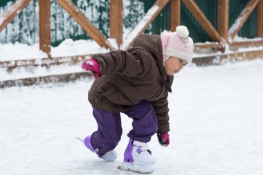 Üç yaşında beyaz bir çocuk kışın paten kayarak paten sahasına düşüyor.