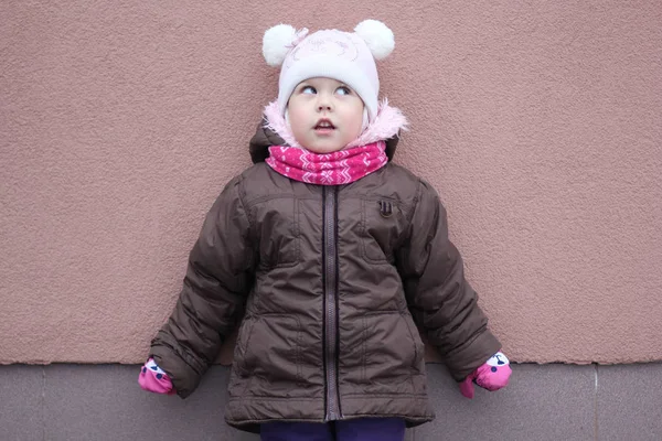 Criança em pano quente na temporada de inverno olhando para cima e à parte no fundo roxo — Fotografia de Stock