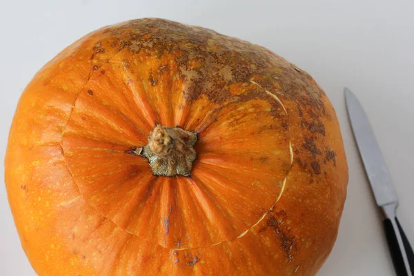 Whole pumpkin after several minutes in oven with cuting top and knife on the white background. Concept how to cut pumpkin with tough peel — 스톡 사진
