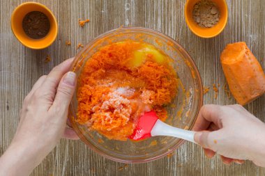 Kadın elleri ahşap arka planda havuçlu turta için hamuru karıştırıyor.