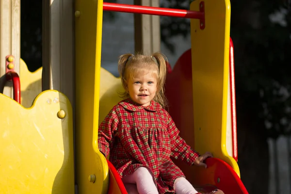Retrato de niño caucásico de dos años mirando a la distancia sentado en el patio de recreo deslizándose —  Fotos de Stock