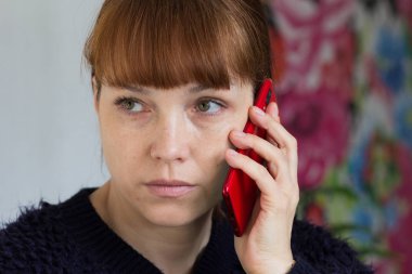 Portrait of the serious middle aged woman holding mobile phone and looking aside
