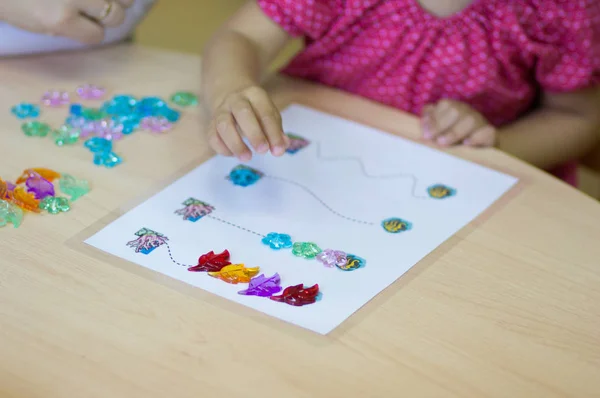 Hareket kabiliyeti geliştirmek için çocuk elleri renkli taşlarla oynuyor.
