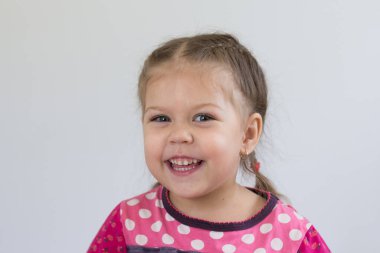 Beyaz arka plandaki kameraya bakan üç yaşında beyaz bir çocuğun portresi.