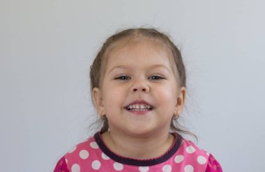 Beyaz arka plandaki kameraya bakan üç yaşındaki beyaz bir çocuğun portresi.