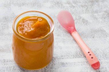 Cam kavanozda kabak püresi ve beyaz arka planda kaşık.