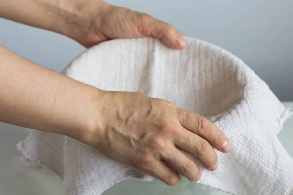 Woman hands putting waffle towel on bowl for making cottage cheese or greek yogurt or cheese
