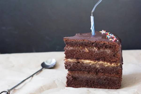 Кусок Слоистого Шоколадного Торта Свечой Света Ложкой Бумаге — стоковое фото