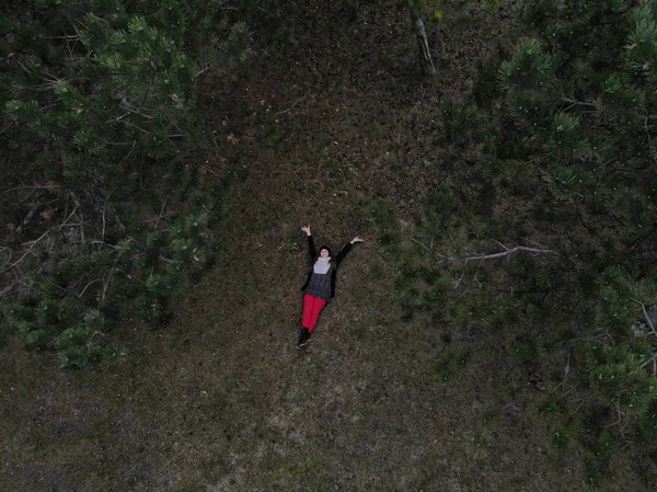Вид сверху на женщину в красных штанах, лежащую в лесу во время выигрыша — стоковое фото