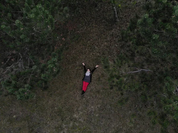 Vista superior de una hembra con pantalones rojos acostada en un bosque durante la victoria — Foto de Stock