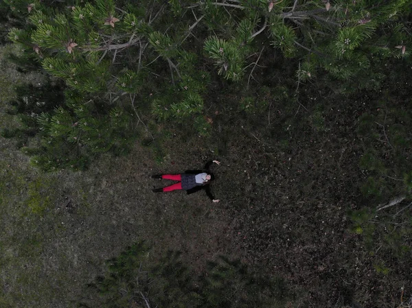 Vista superior de una hembra con pantalones rojos acostada en un bosque durante la victoria — Foto de Stock