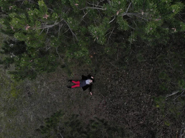 Vista superior de una hembra con pantalones rojos acostada en un bosque durante la victoria —  Fotos de Stock