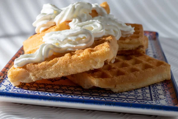 Vista próxima de waffles com creme em uma placa azul isolada em um w — Fotografia de Stock