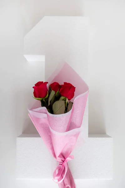 Bouquet of Red Roses in pink Paper on a One Number, anniversary — Stock Photo, Image